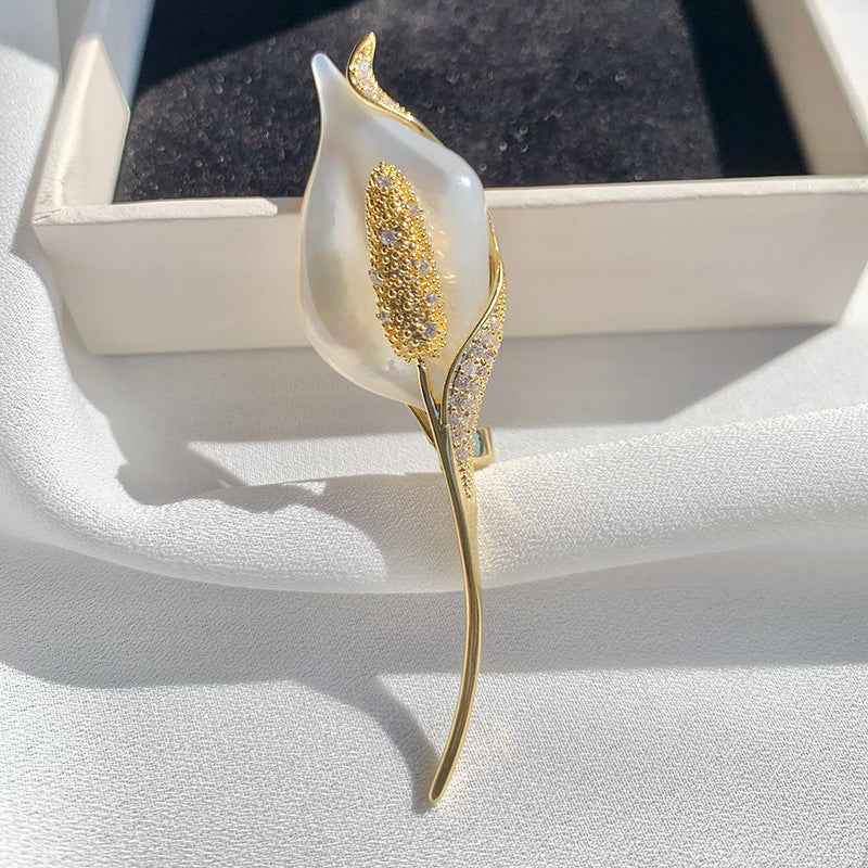 Sea shell tulip brooch on display: white pearly petals with glittery gold leaf details