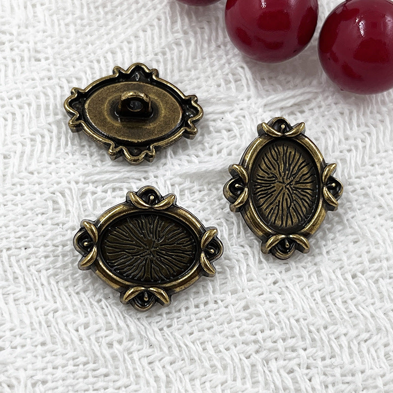 Gold-toned oval metal shank buttons with engraved floral motif and circular backing