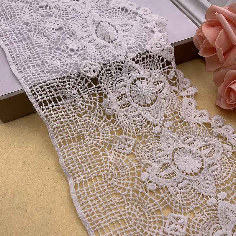 White embroidered cotton lace trim close-up with two floral motifs and openwork pattern