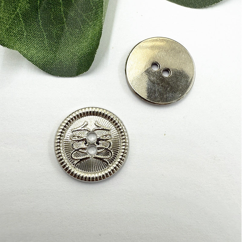 Two-hole metal button with floral filigree, silver tone; flat back shown