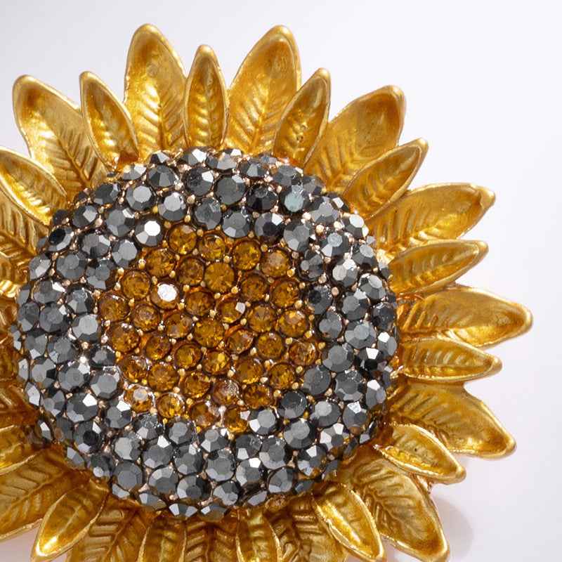 Close-up sunflower brooch: gold leaf rim with dark and amber sparkling crystals