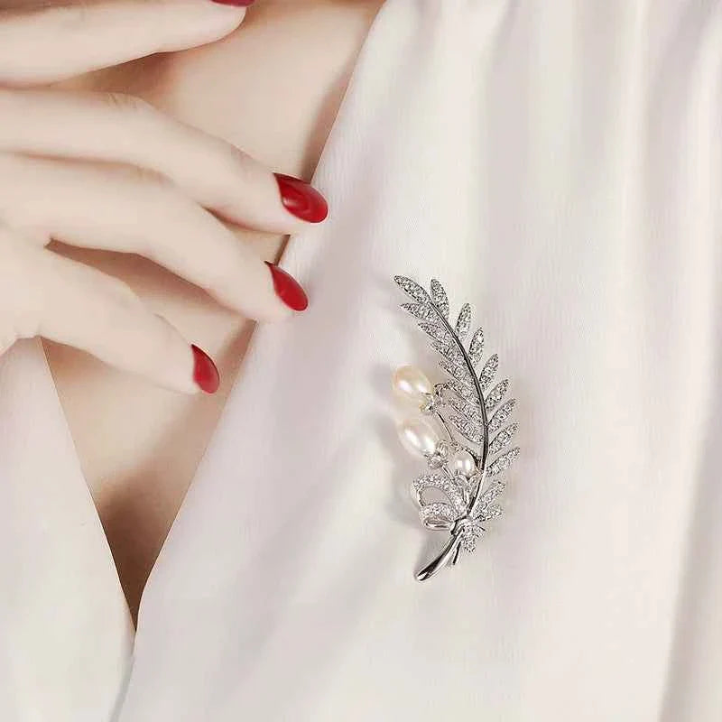 Silver wheat leaf brooch pin with zircons and natural pearls, held on fabric