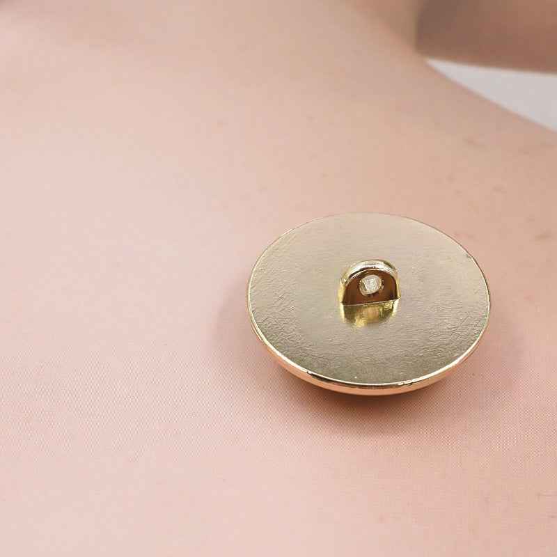 Round gold metal shank button, front view with center sew-through hole
