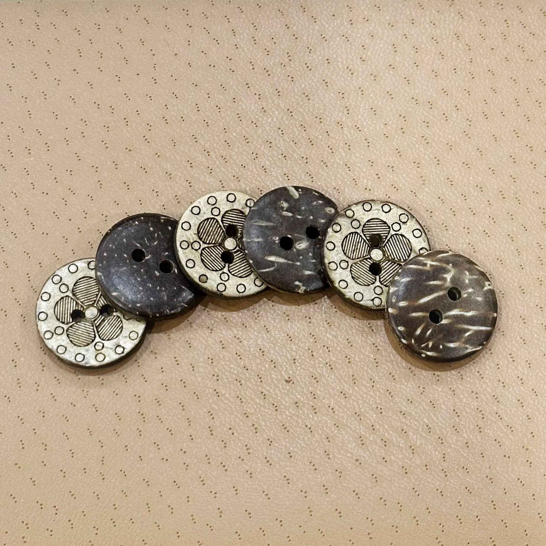 Round coconut shell buttons in a line: dark blue-gray fronts and white floral laser details