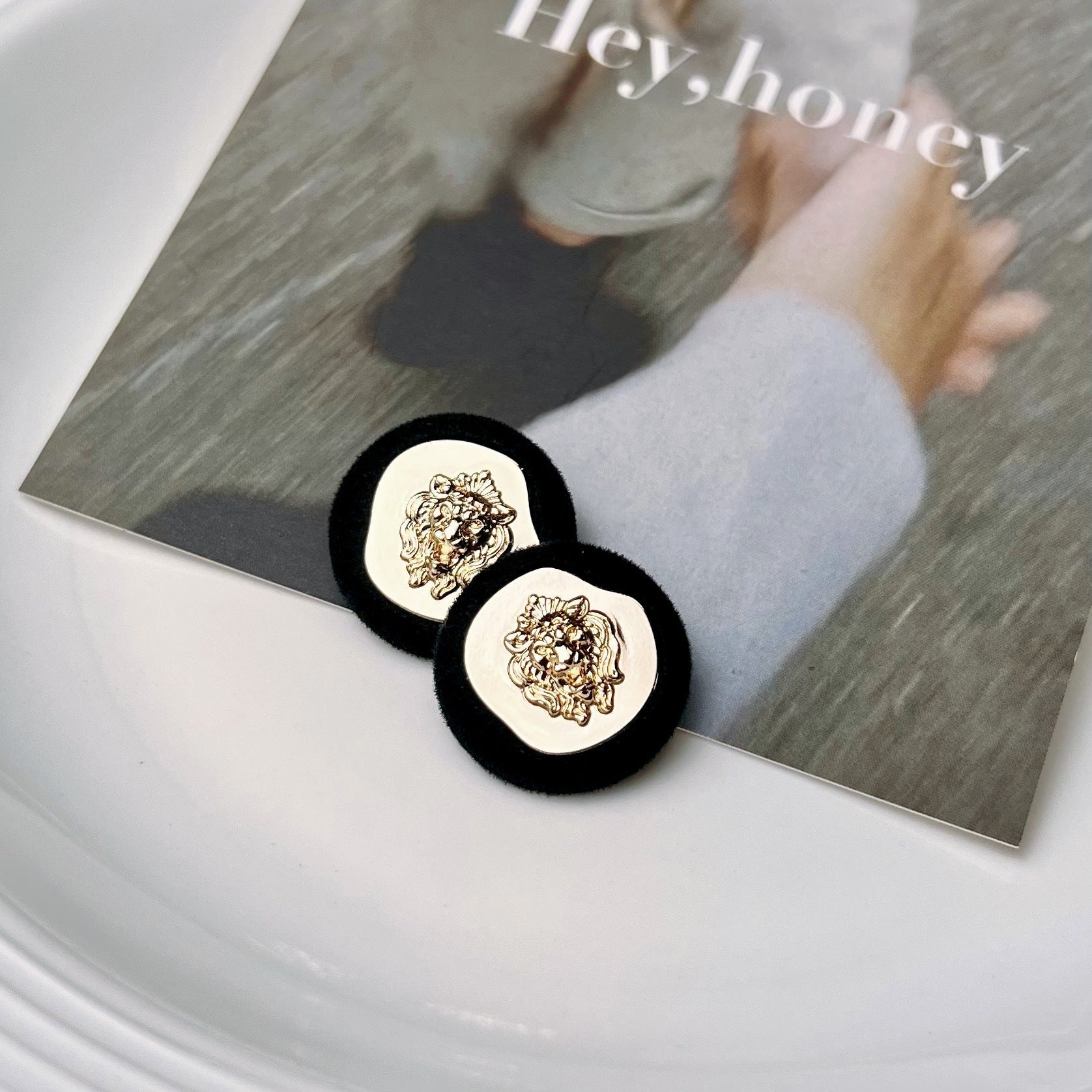 Two black blazer buttons with gold lion-head medallion on round base