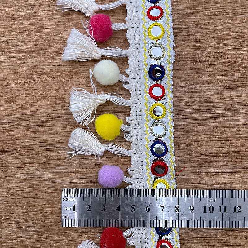 White pom-pom trim with colorful ring embroidery and long tassel fringe along the border.