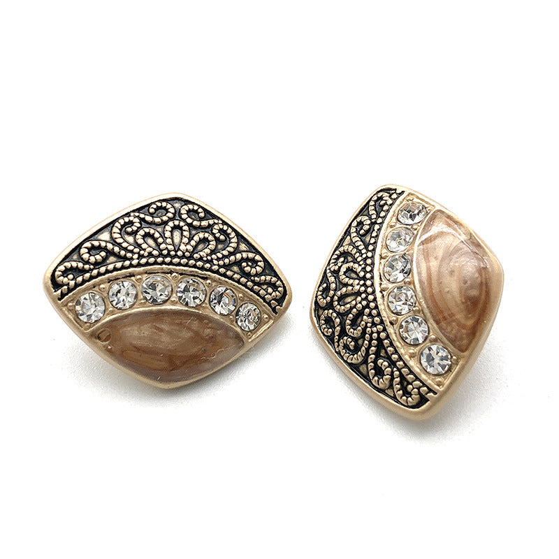 Metal shank button with black filigree border, clear rhinestones, and tan pearl panel