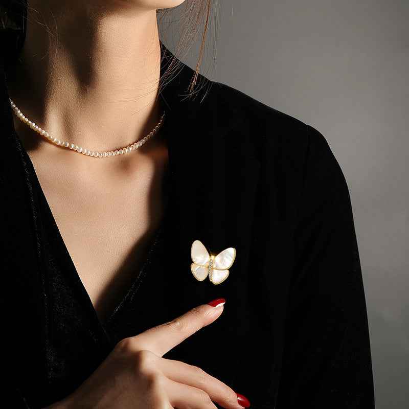 Butterfly brooch pin with white shell wings and zircon center, worn on neckline, Color A