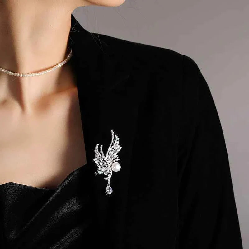 Silver wing brooch pin with sparkling stones and round pearl accent on lapel