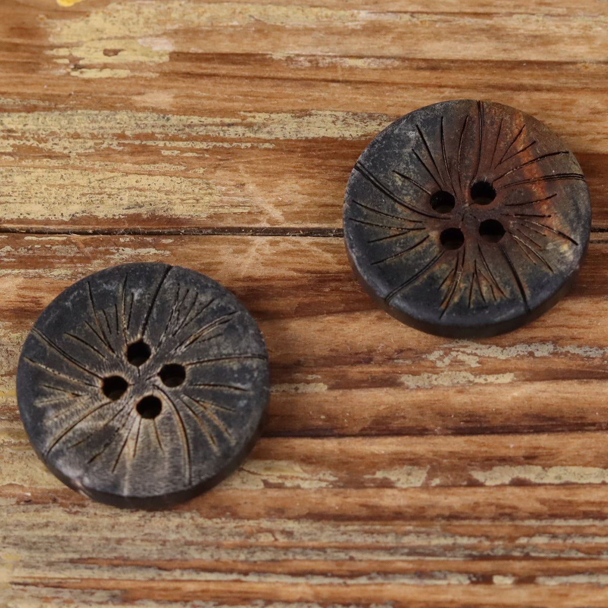 Two dark round 4-hole horn buttons with radiating etched lines