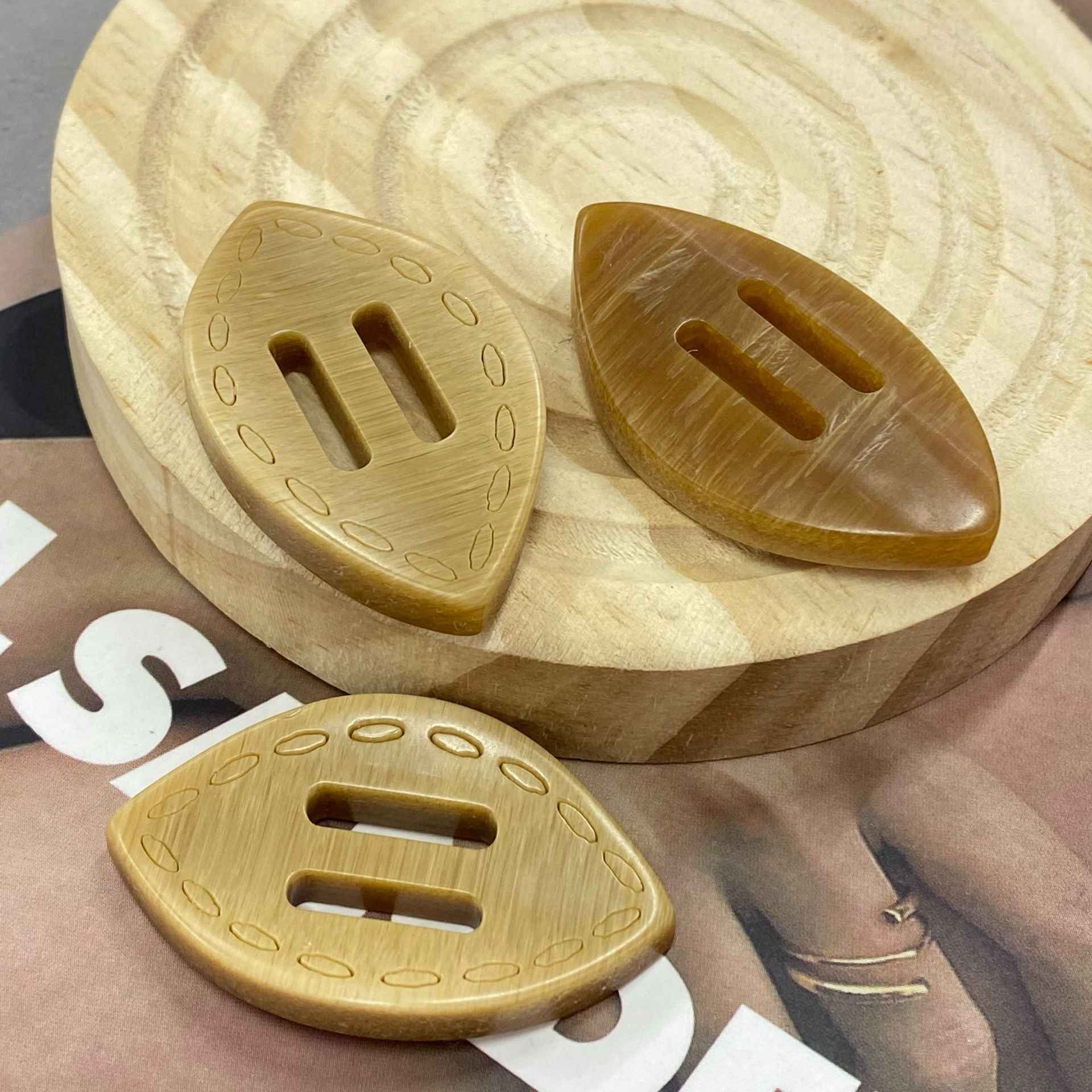 Gold-toned oval resin 2-hole buckle buttons, oval cutouts with stitched border detail