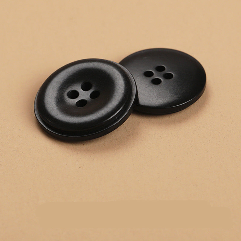 Two round 4-hole natural fruit shell buttons, black, side-by-side