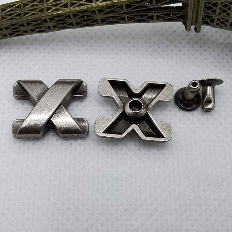 X-shaped metal rivet studs with prongs and dark round insert, silver/black finish.