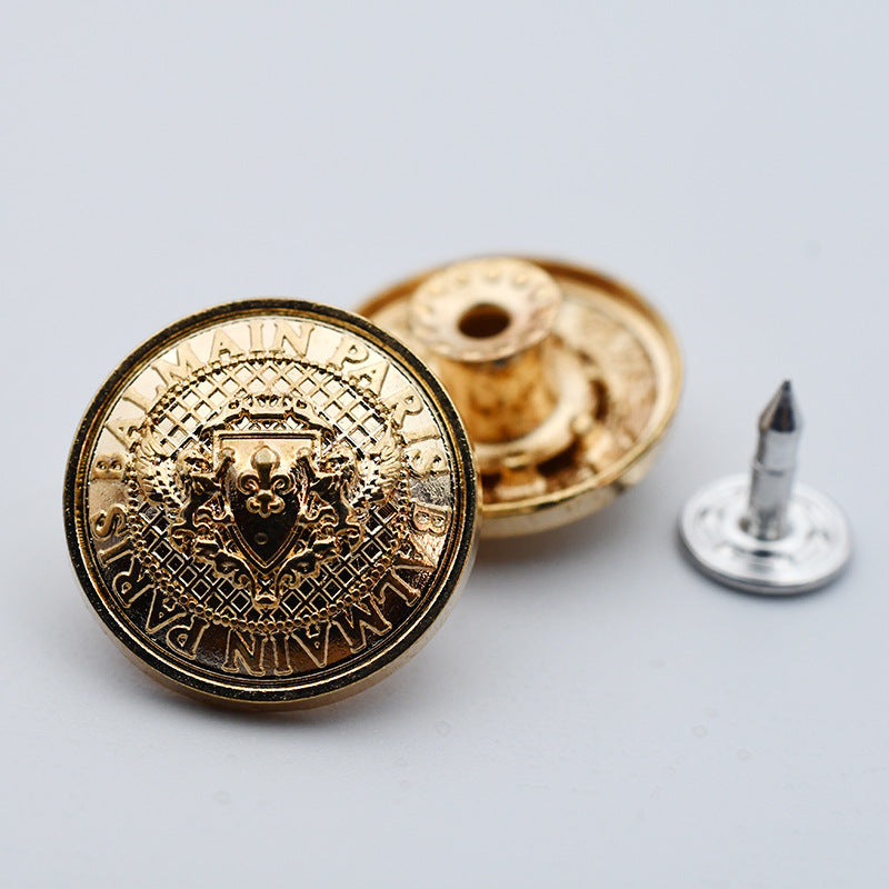 Round gold metal shank stud button with detailed crest front and pointed post back