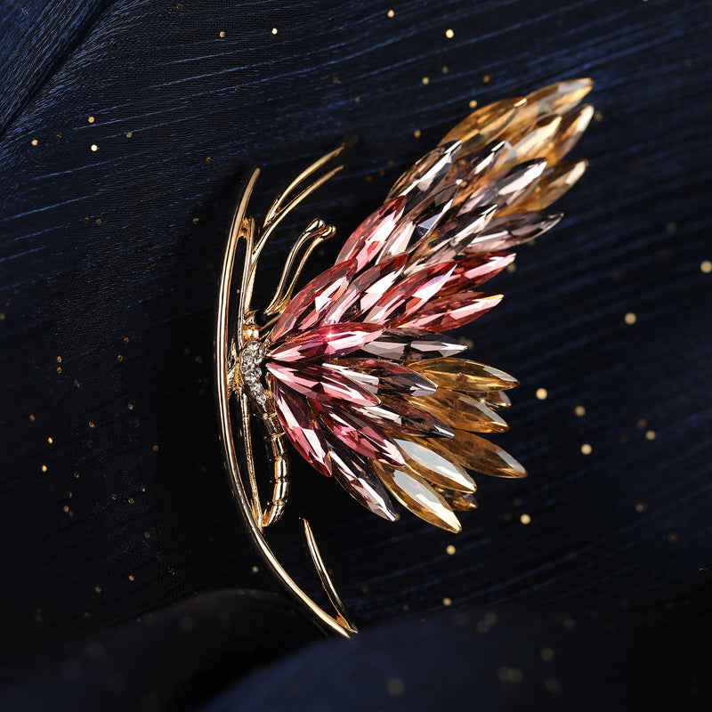 Crystal butterfly brooch close-up: red and amber faceted wings with rhinestone center