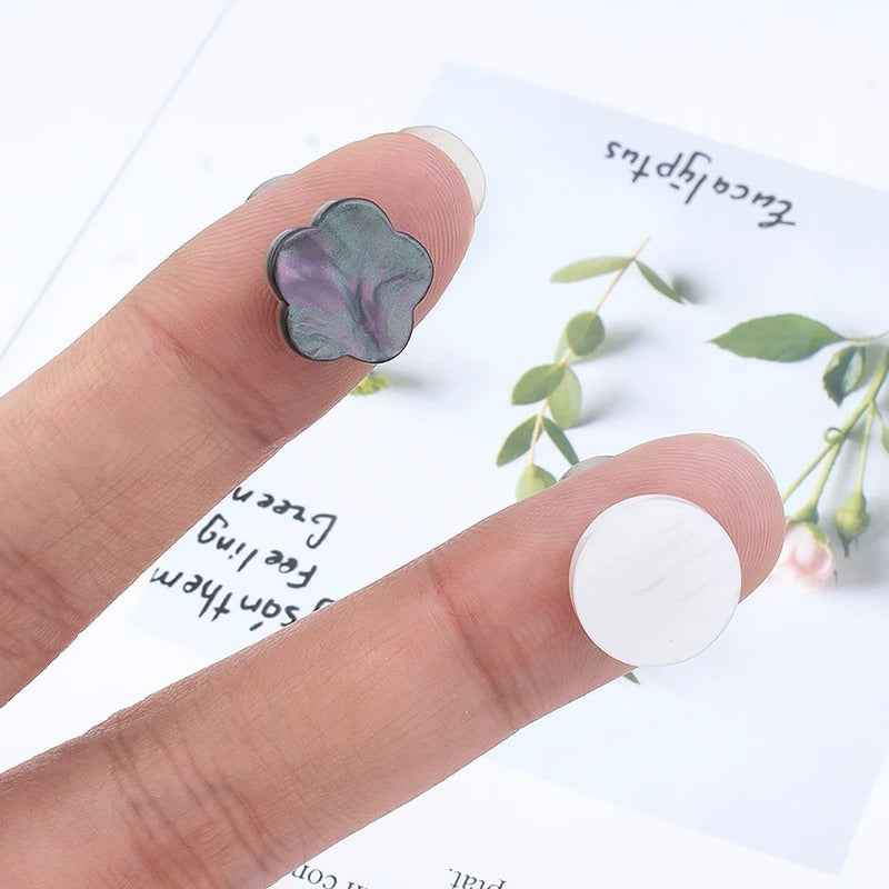 Magnetic collar clip, clover flower design in dark gray held between fingers