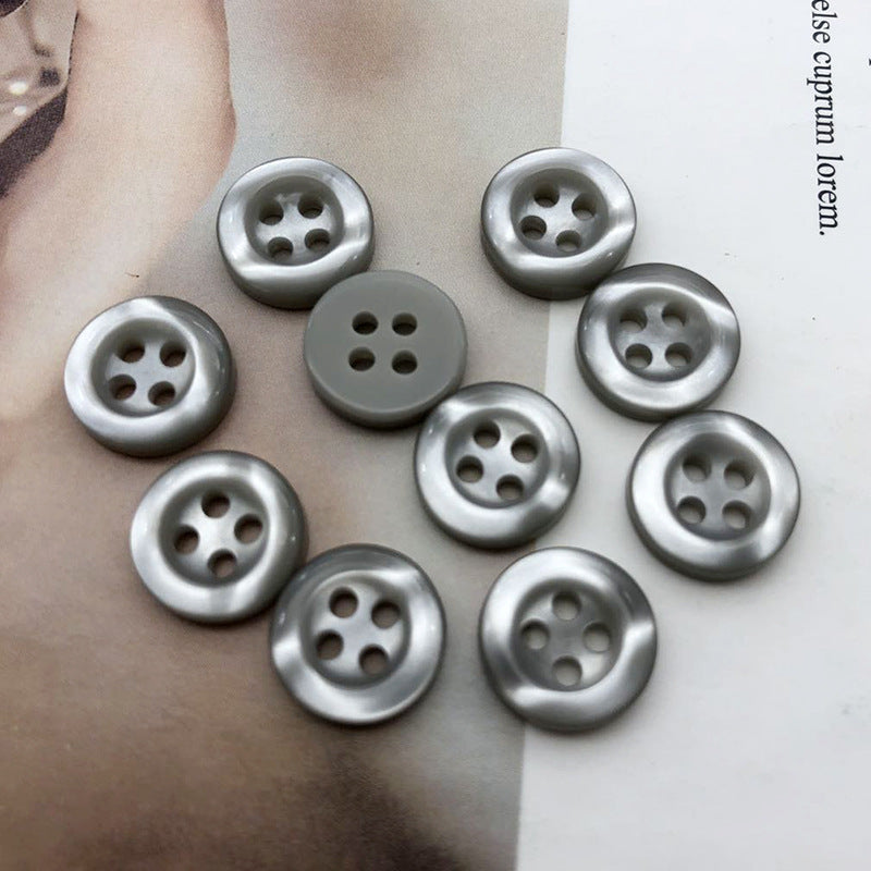 Round resin shirt buttons, 4-hole, silvery grey mix, laid on fabric