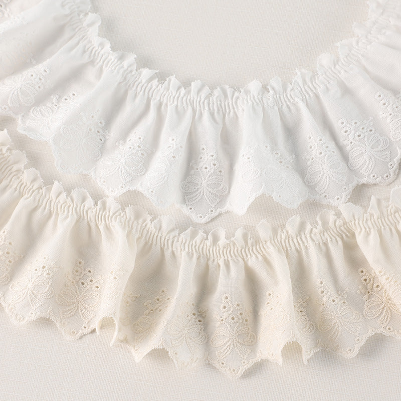 Off-white pleated lace trim with embroidered motifs, scalloped edges and gathered top