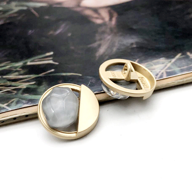 Runder Mantelknopf mit grauem Stein, goldfarbener Metallfassung und Wellenrand