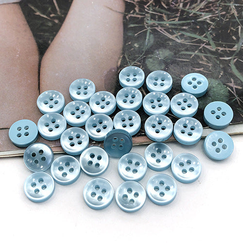 Light sky-blue round 4-hole shirt buttons, assorted buttons showing four holes