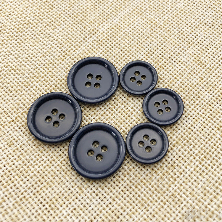 Navy 4-hole round resin cuff buttons, close-up view of several buttons on beige cloth