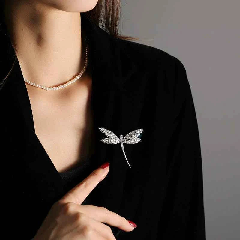 Dragonfly brooch worn on black blazer lapel, silver-tone with zircon sparkle