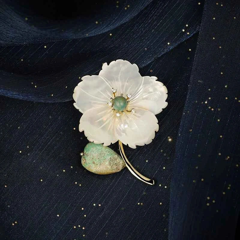 Muschelblüten-Brosche: weiße Blüte, türkisfarbene Perle, goldfarbene Akzente