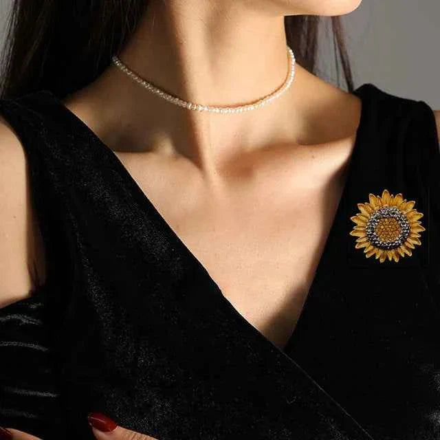 Sunflower crystal lapel pin on a black dress, gold-tone petals and rhinestone center