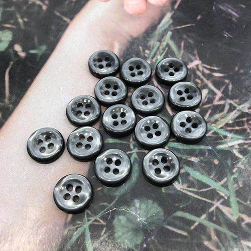 Round resin shirt buttons, 4-hole, dark grey assortment held in hand