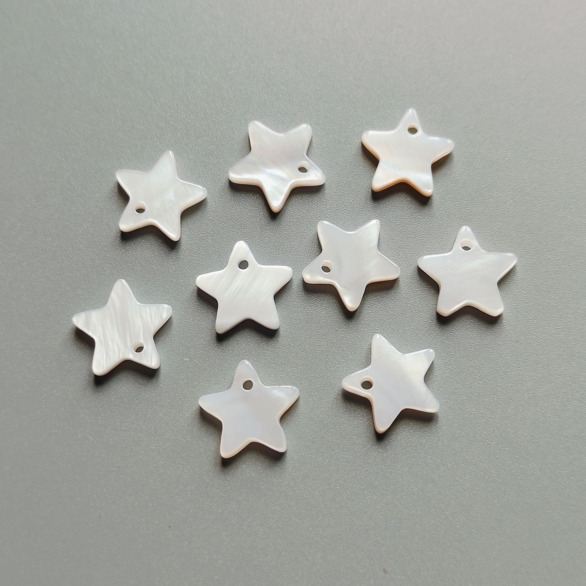 White five-point star shell buttons, single-hole, multiple pieces shown