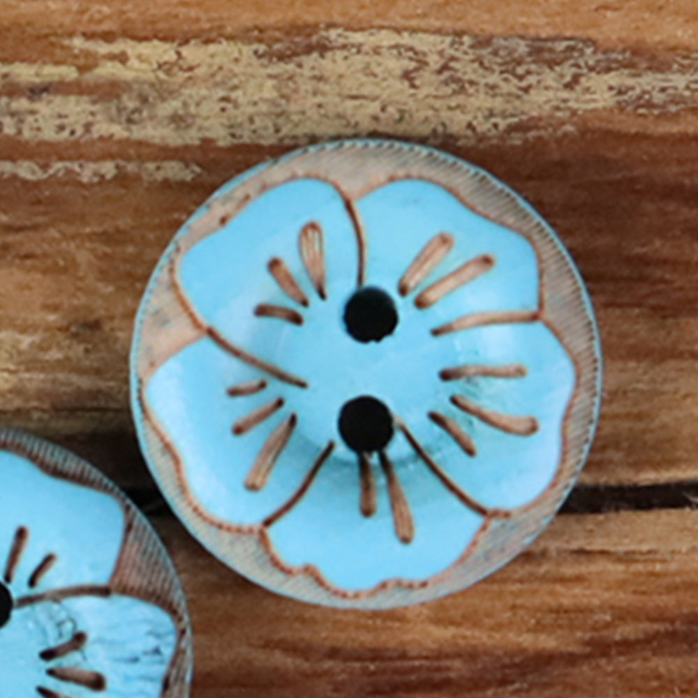 Round 2-hole wood button with painted floral pattern in light blue with dark center holes.