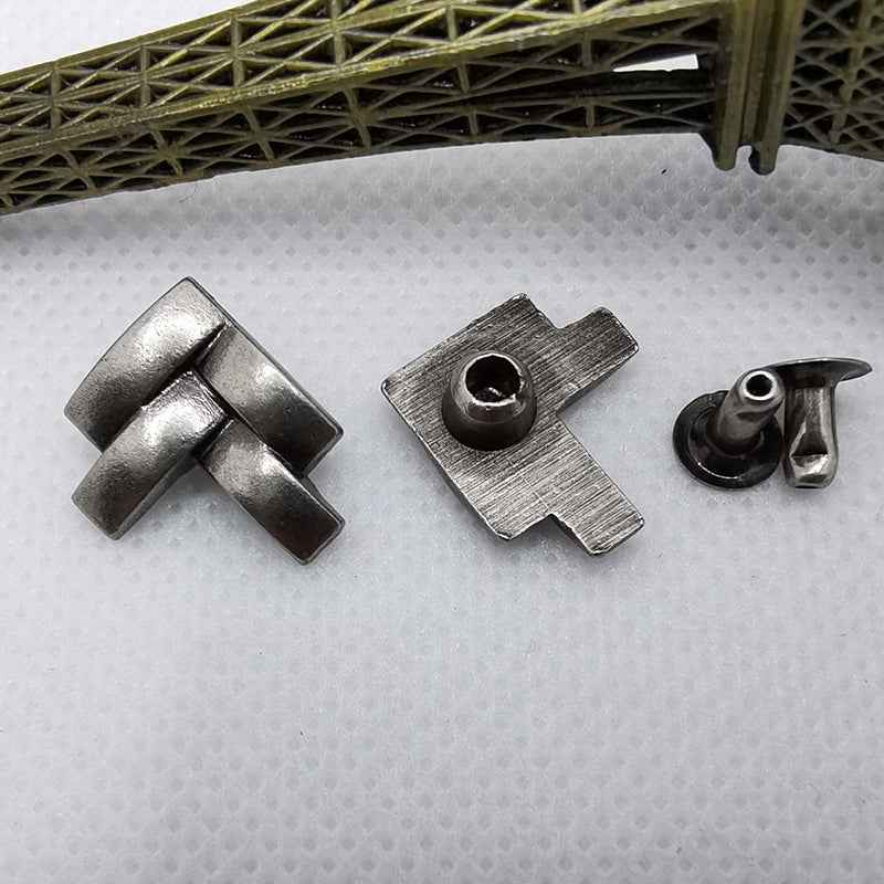Close-up of metal X-shaped rivet studs with flat base and hole center, silver tone.