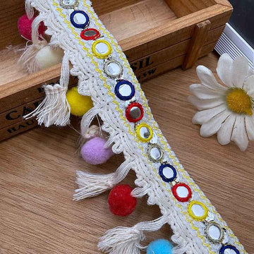 White embroidered jacquard trim with tassels, pom-poms, and colorful ring accents.