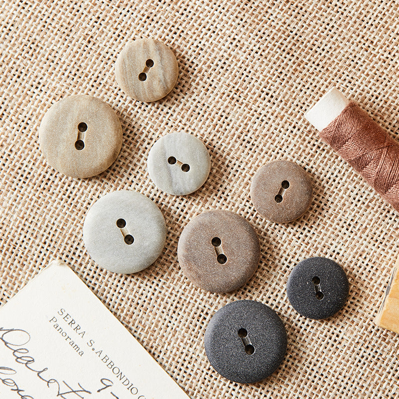 Round two-hole eco-resin buttons in light grey, khaki, brown, and black