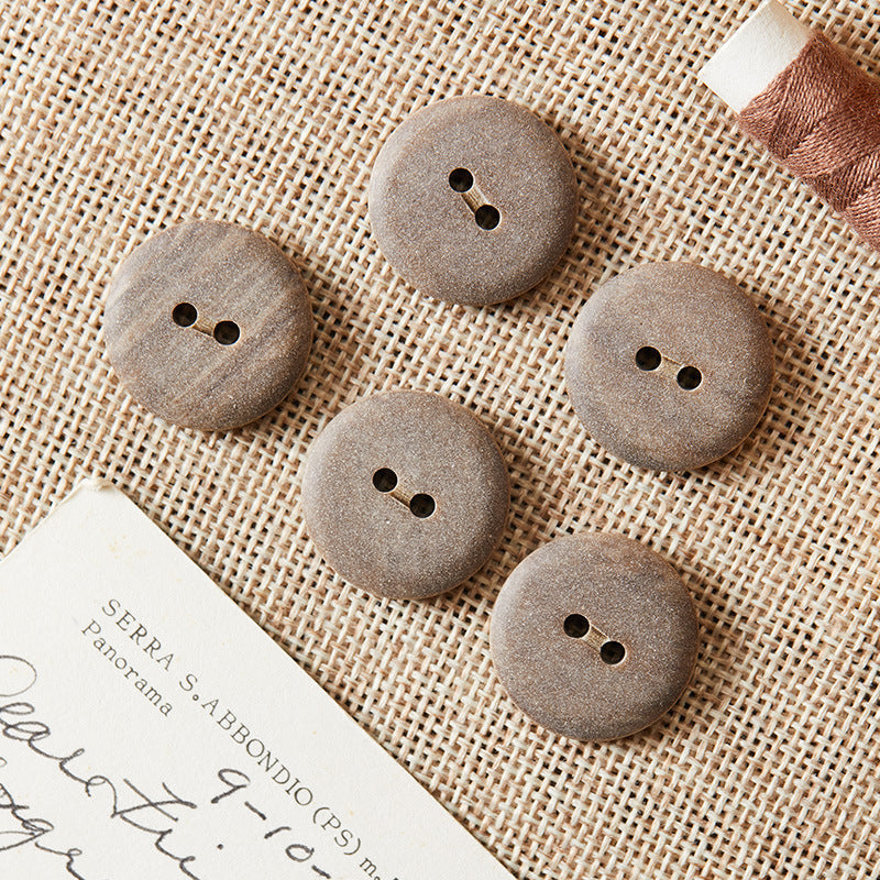 Round two-hole eco-resin buttons in light grey, brown, and khaki tones