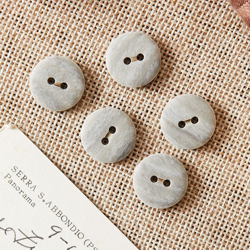 Round two-hole eco-resin buttons in light grey, with two holes on top