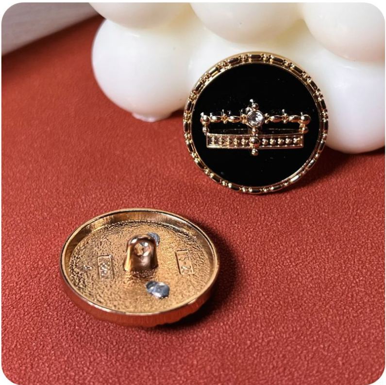 Back and front of black crown glue button with gold-tone metal shank attachment