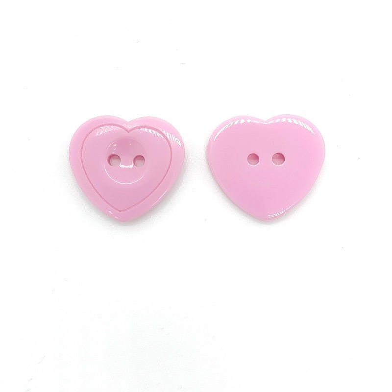 Pink heart-shaped resin craft button with two holes, glossy front view
