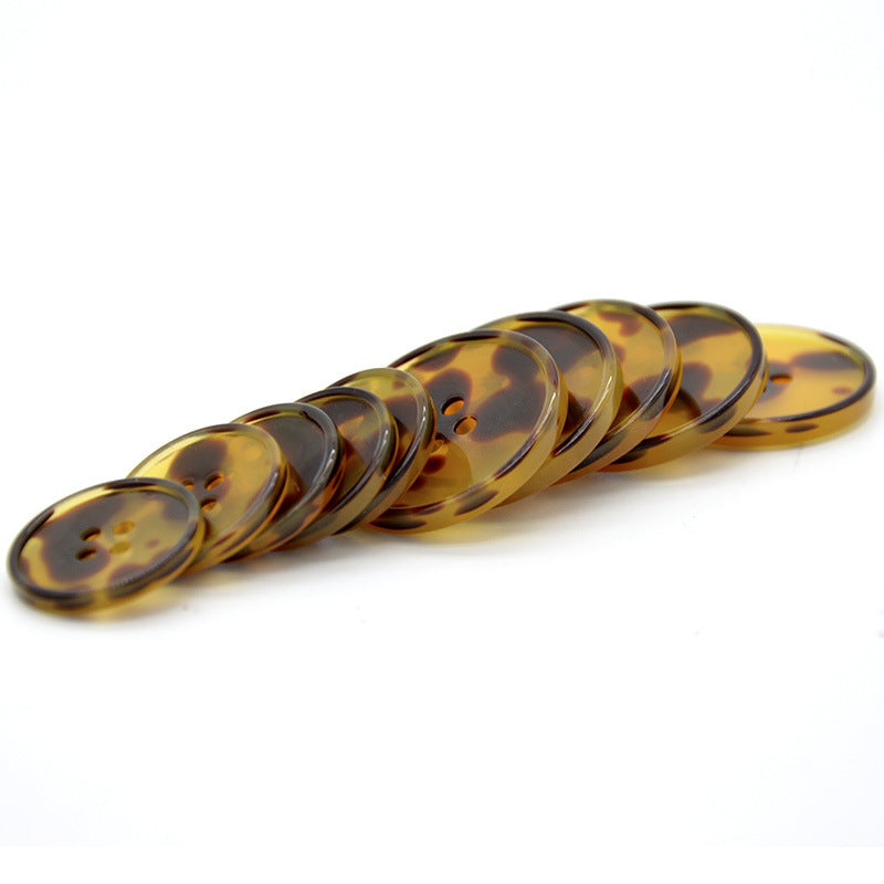 Brown leopard resin buttons, round with four holes; buttons lined in a row