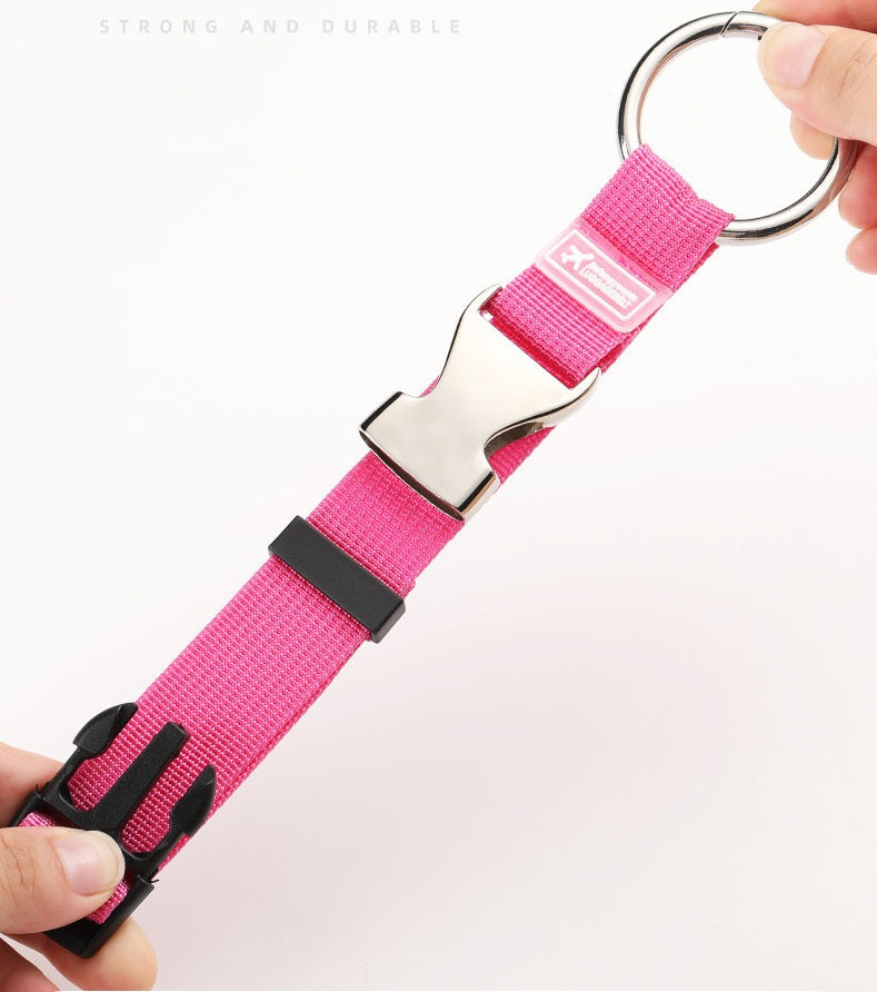 Pink luggage strap detail with metal ring hook and black buckle