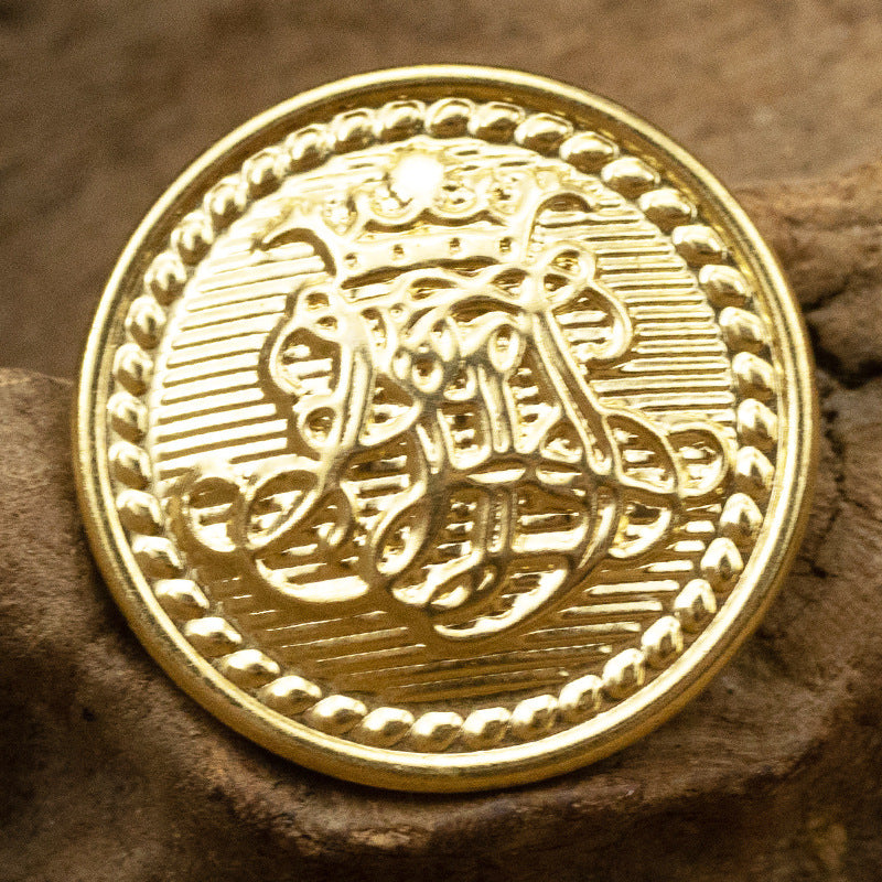 Gold metal shank button close-up front with note emblem and laurel detail