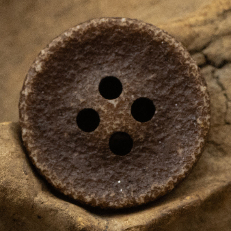 Chocolate brown distressed resin button, four holes, speckled textured surface.