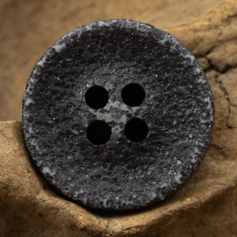 Deep blue distressed resin button, four holes with mottled weathered texture.