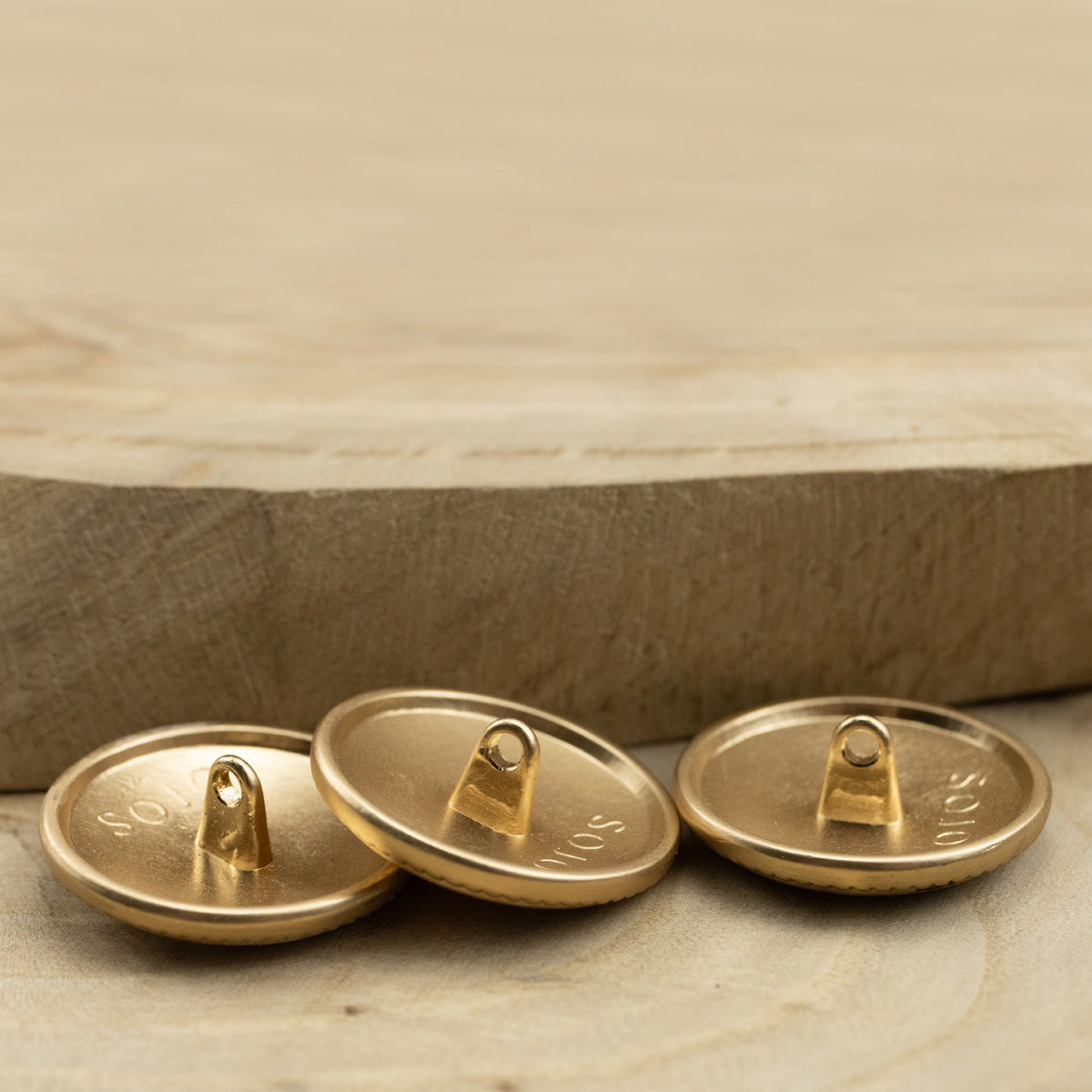 Gold metal shank buttons underside with stitched shank posts and front-edge rim