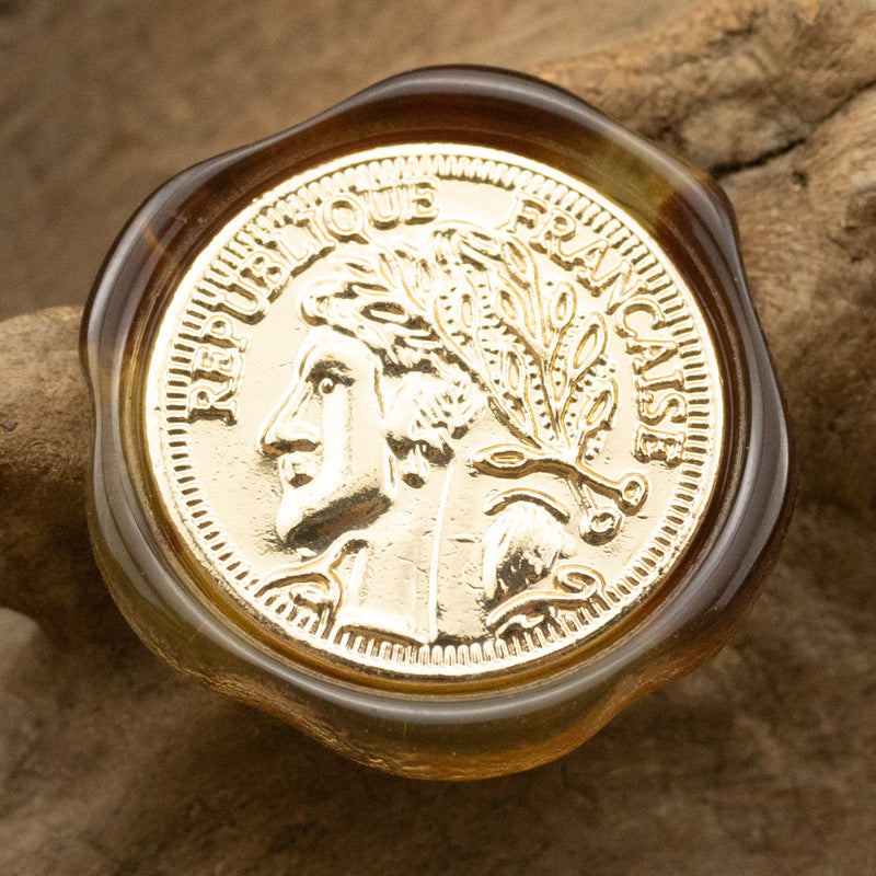 Irregular resin shank button, coffee-brown translucent, gold portrait with ornate border