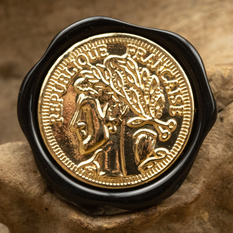 Irregular resin shank button, black/dark resin, gold-tone portrait and ornate rim