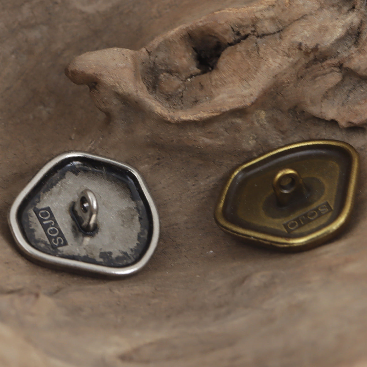 Back view of metal shank buttons, silver and bronze ovals with loop shanks
