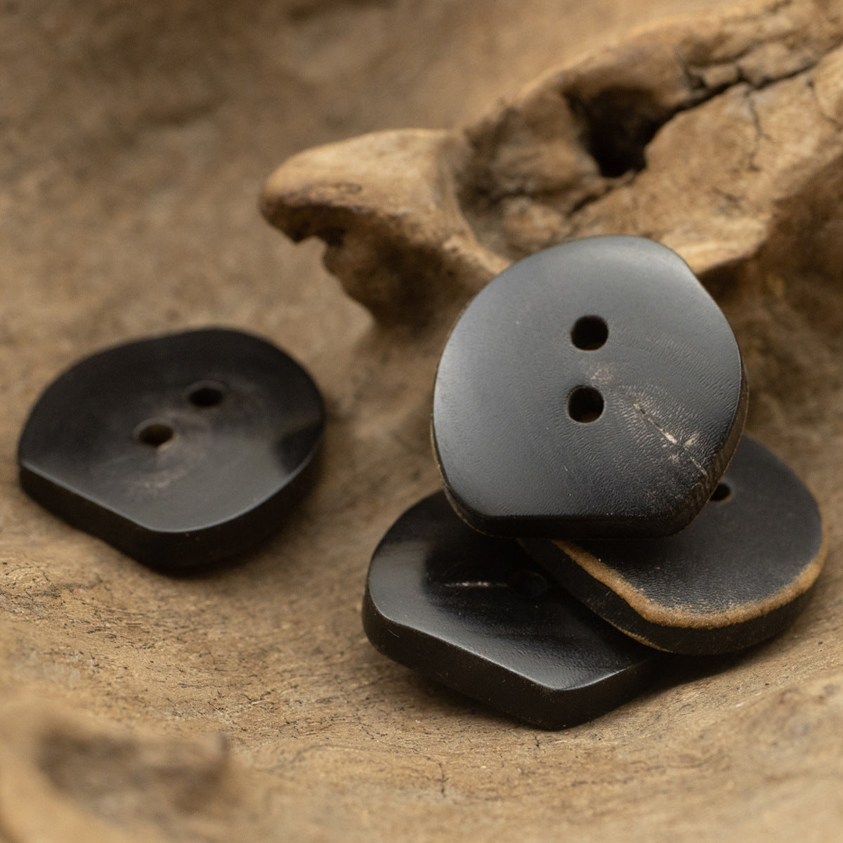 Irregular dark horn buttons with two holes, vintage finish, 3pcs including angled view