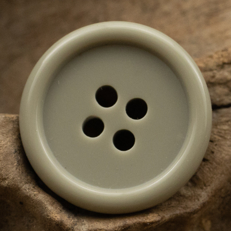Ivory/cream resin suit button with four holes, smooth solid color front
