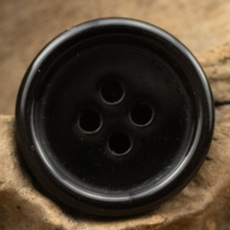 Black resin suit button with four holes, smooth solid color front